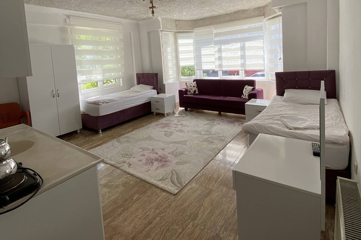 A bedroom with a bed, a sofa, a desk, and a wardrobe.