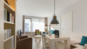 Ett modernt vardagsrum med en soffa, ett matbord och en bokhylla.