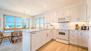 A modern kitchen with white cabinets, a built-in microwave, and a large island with seating.