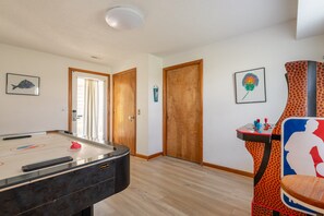 Una habitación con mesa de billar, mesa de futbolín y una puerta que da a otra estancia.