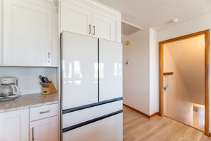 Cocina con alacenas blancas, refrigerador y cafetera.
