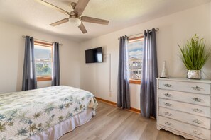 Un dormitorio con cama, cómoda, televisor y ventilador de techo.