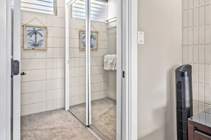 A bathroom with a glass shower door, a towel rack with a white towel, and a black portable heater.