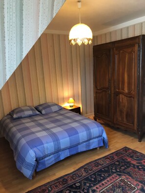 Une chambre à coucher avec un lit, une table de chevet, une lampe, une armoire et un tapis à motifs.