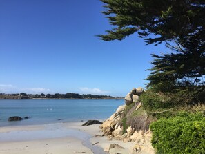 A beach with clear blue water, sandy shore, and rocky outcrops. - Beach house (Kerlouan)