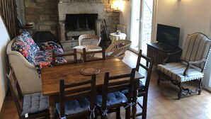 Una sala de estar acogedora con chimenea de piedra, muebles de madera y televisor.