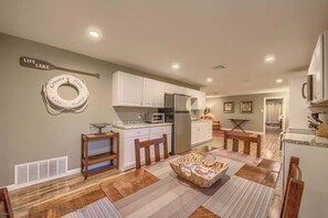 A kitchen with white cabinets, a refrigerator, a microwave, and a dining area with a table and chairs.