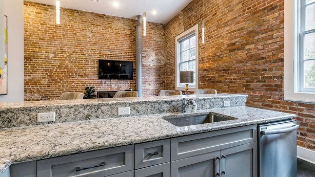 A kitchen with granite countertops, a built-in dishwasher, and a brick wall. - DOWNTOWN 2BR Walk to Superdome,Parade French Quarter (New Orleans)