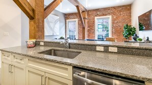Una cocina con encimeras de granito, electrodomésticos de acero inoxidable y vigas de madera a la vista.