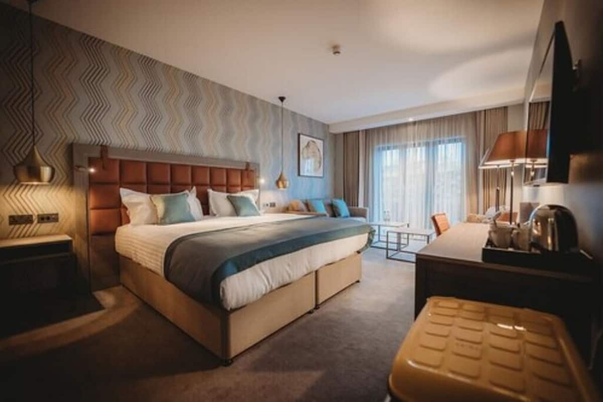 Ein modernes Hotelzimmer mit einem großen Bett, einem Schreibtisch und Blick auf die Stadt.
