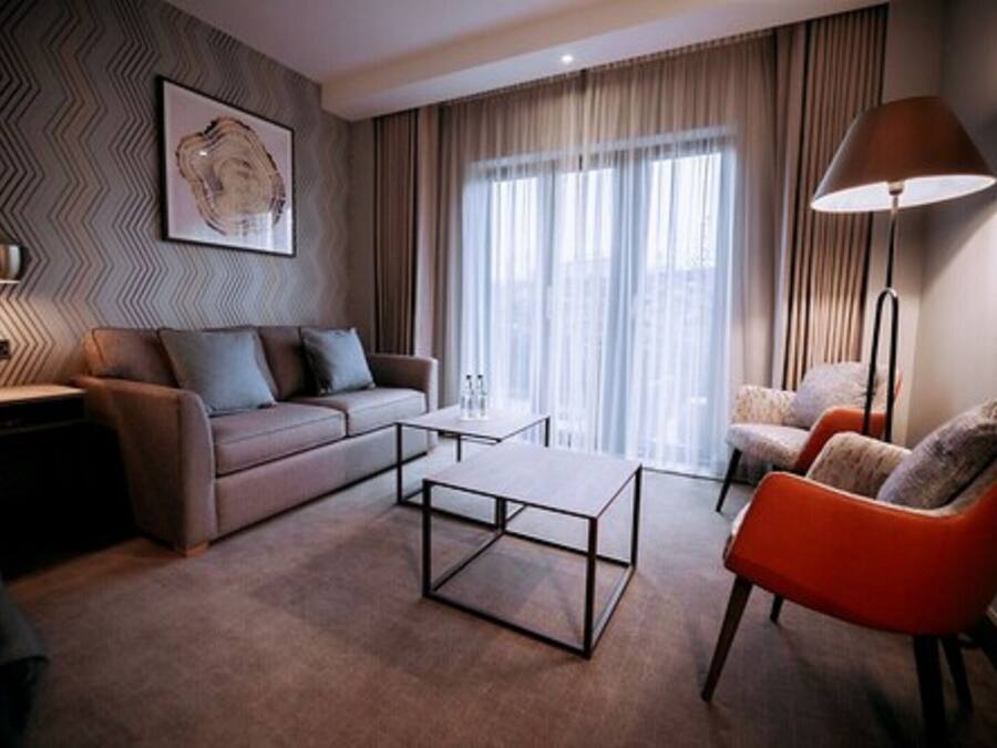 A modern living room with a sofa, two armchairs, a coffee table, and a floor lamp.