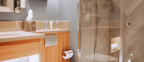 A modern bathroom with a glass-enclosed shower, a wooden vanity, and a toilet.