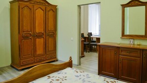 Ein Schlafzimmer mit einem hölzernen Kleiderschrank, einem Bett mit blumigem Überwurf, einer Kommode und einem Spiegel.