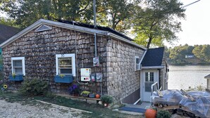 A rustic wooden house with a small porch, a window with shutters, and a door. - Your Cottage on the Lake (Dudley)