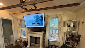 A living room with a fireplace, television, and a stone fireplace surround. - Your Cottage on the Lake (Dudley)