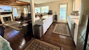 A spacious kitchen with a large island, a dining area with a couch, and a fireplace. - Your Cottage on the Lake (Dudley)