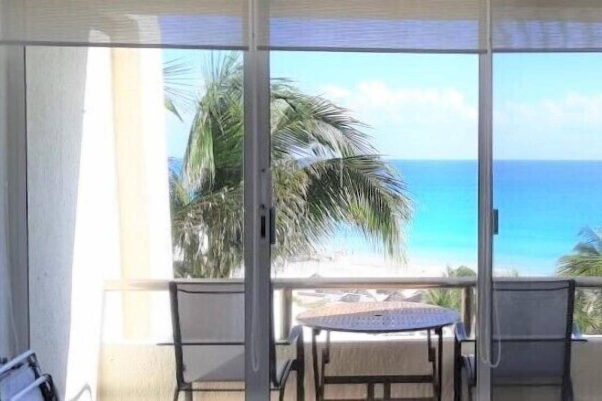 Un balcon avec vue sur l’océan et les palmiers.