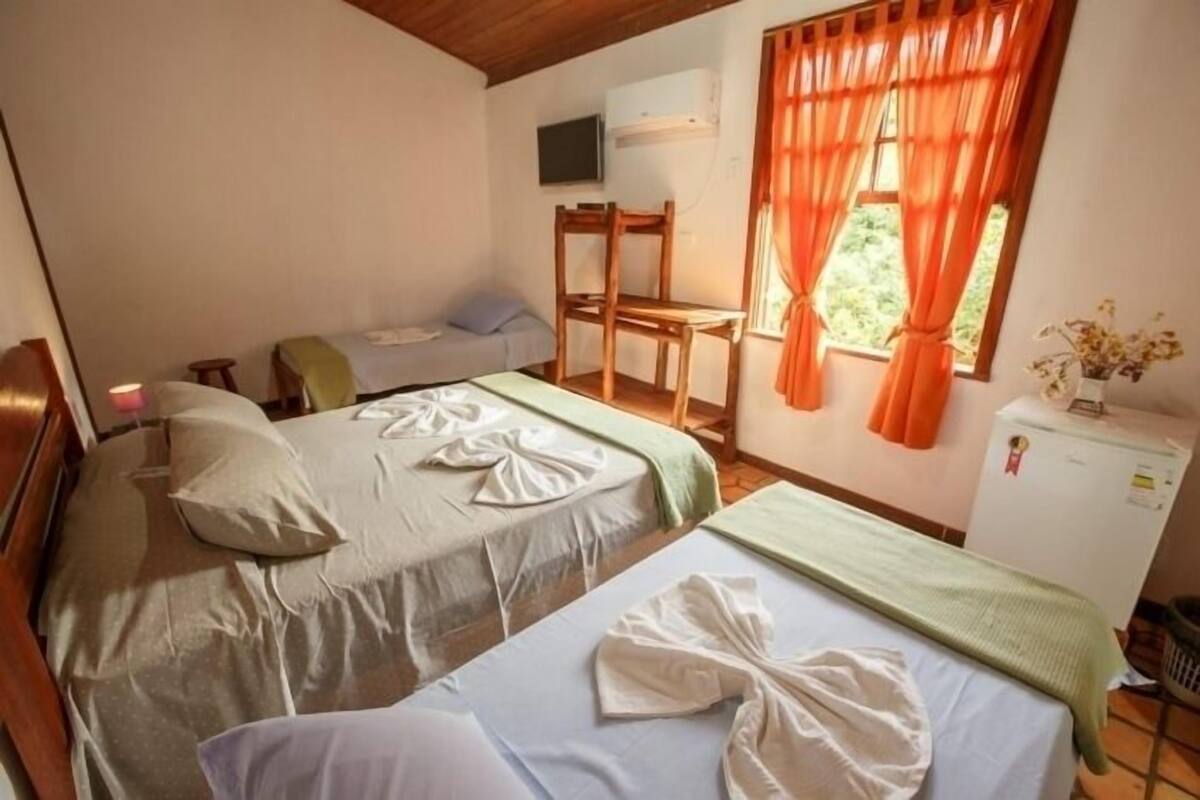 A room with two beds, a desk, and a refrigerator.