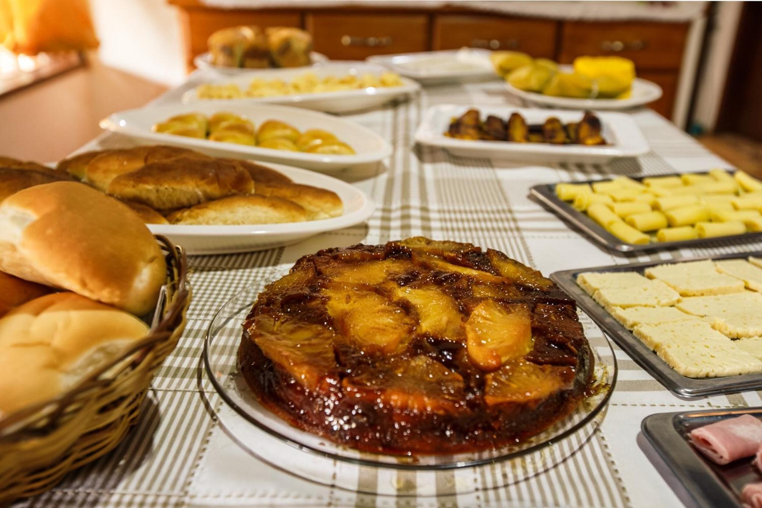 Una mesa de bufé con diversos platos, incluyendo un jamón glaseado, panes y otras opciones de comida.