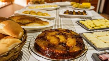 A buffet table with various dishes including a glazed ham, rolls, and other food items.