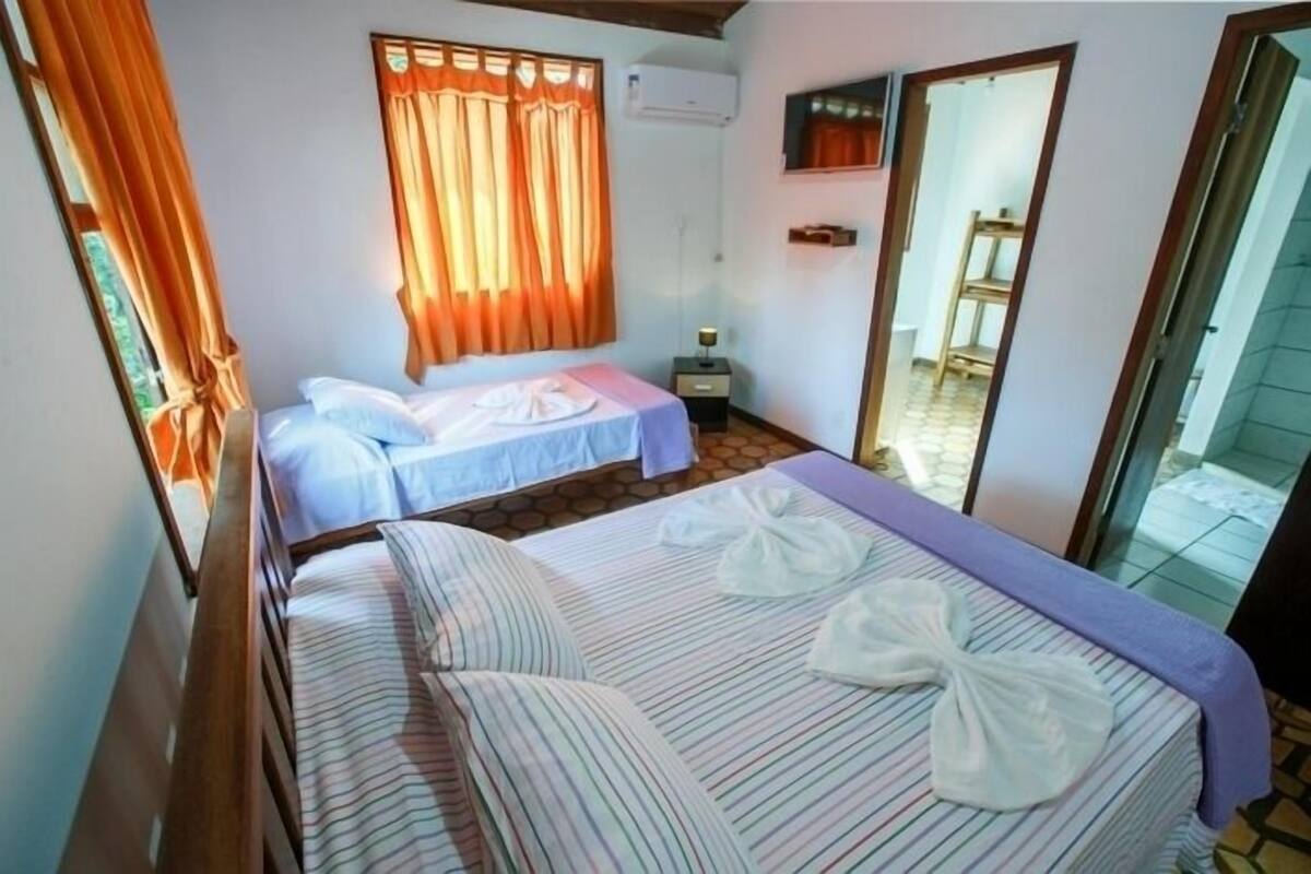 A room with two beds, a small table, and a mirror.