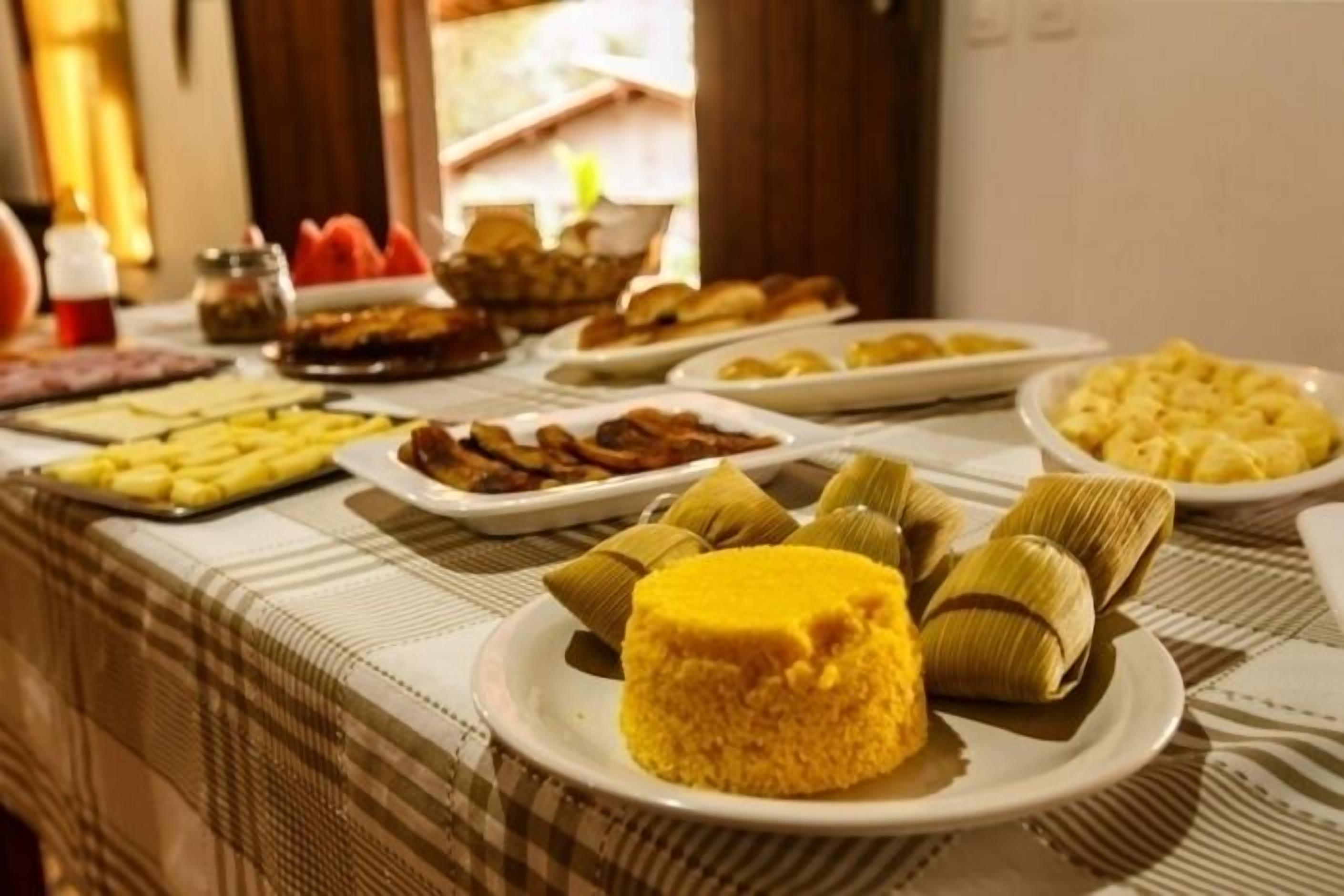 Una mesa de buffet con diversos platos, incluyendo tamales, un arroz amarillo y otras opciones de comida.