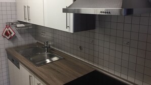 Une cuisine moderne avec des meubles blancs, un évier en acier inoxydable et un plan de travail noir.