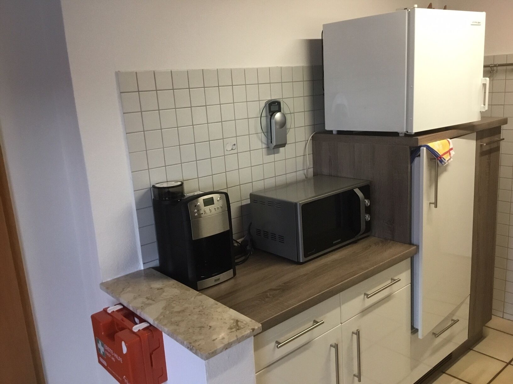 A compact kitchen with a microwave, coffee maker, and a refrigerator.