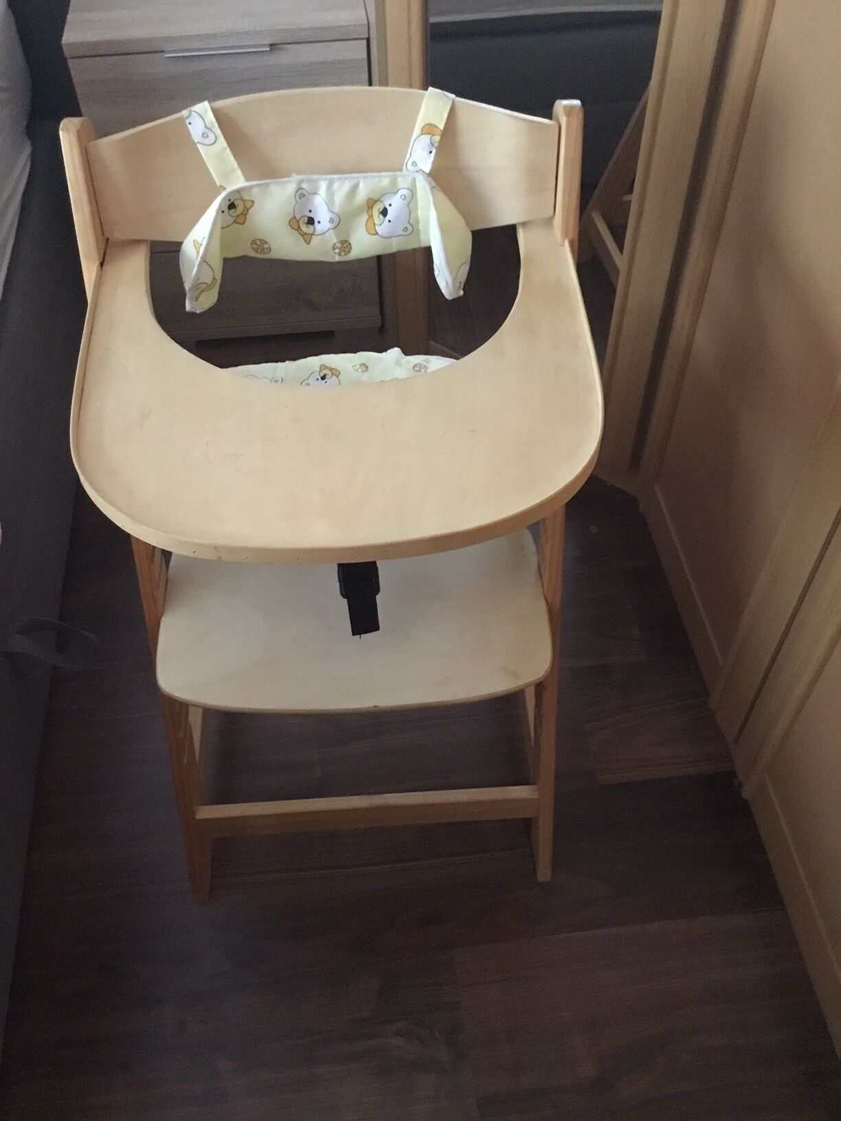 Una trona de madera con asiento acolchado y una bandeja inferior.