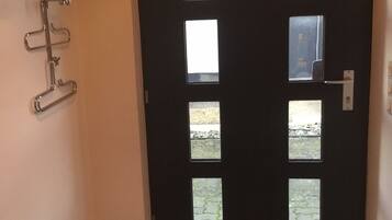A dark wooden door with multiple windows, a fire extinguisher, and a metal rack on the wall.