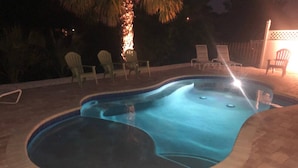 Una piscina a forma curva, circondata da un patio in mattoni.