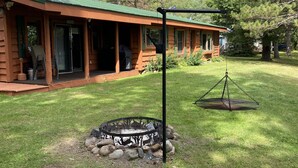 Eine Lodge mit überdachter Veranda, Feuerstelle und einer hängenden Laterne.