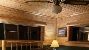 Ein Holzblockraum mit Bett, Tisch und Deckenventilator.