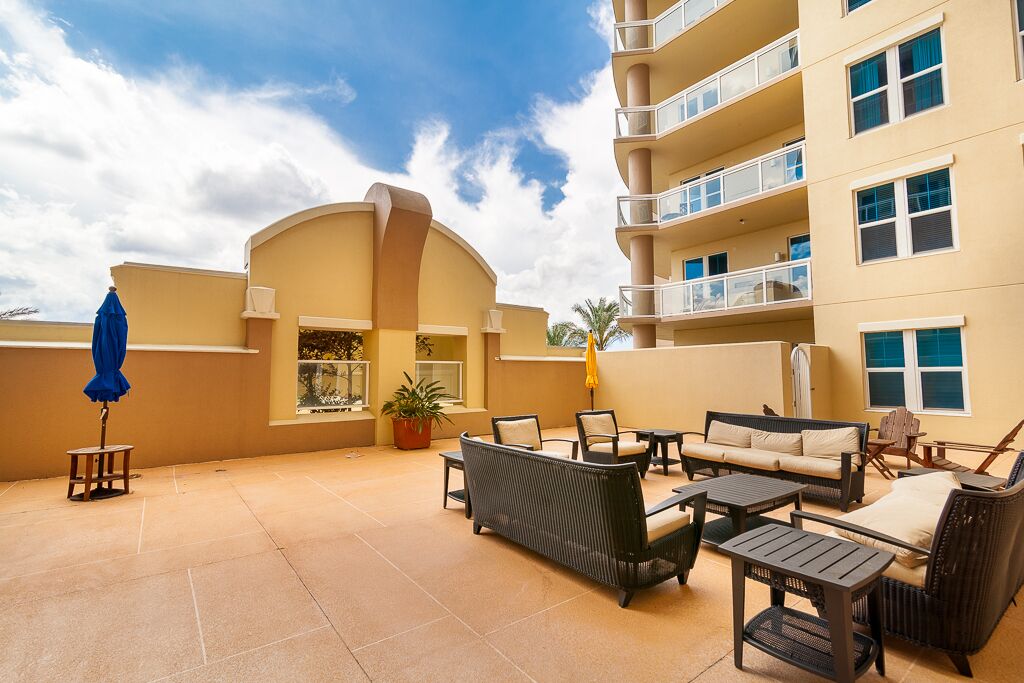 Un patio de hotel con mobiliario exterior, una sombrilla azul y una planta en maceta.
