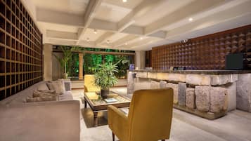 Un vestíbulo moderno con un sofá, sillones, una mesa de centro, un mostrador de recepción y una pared decorativa.
