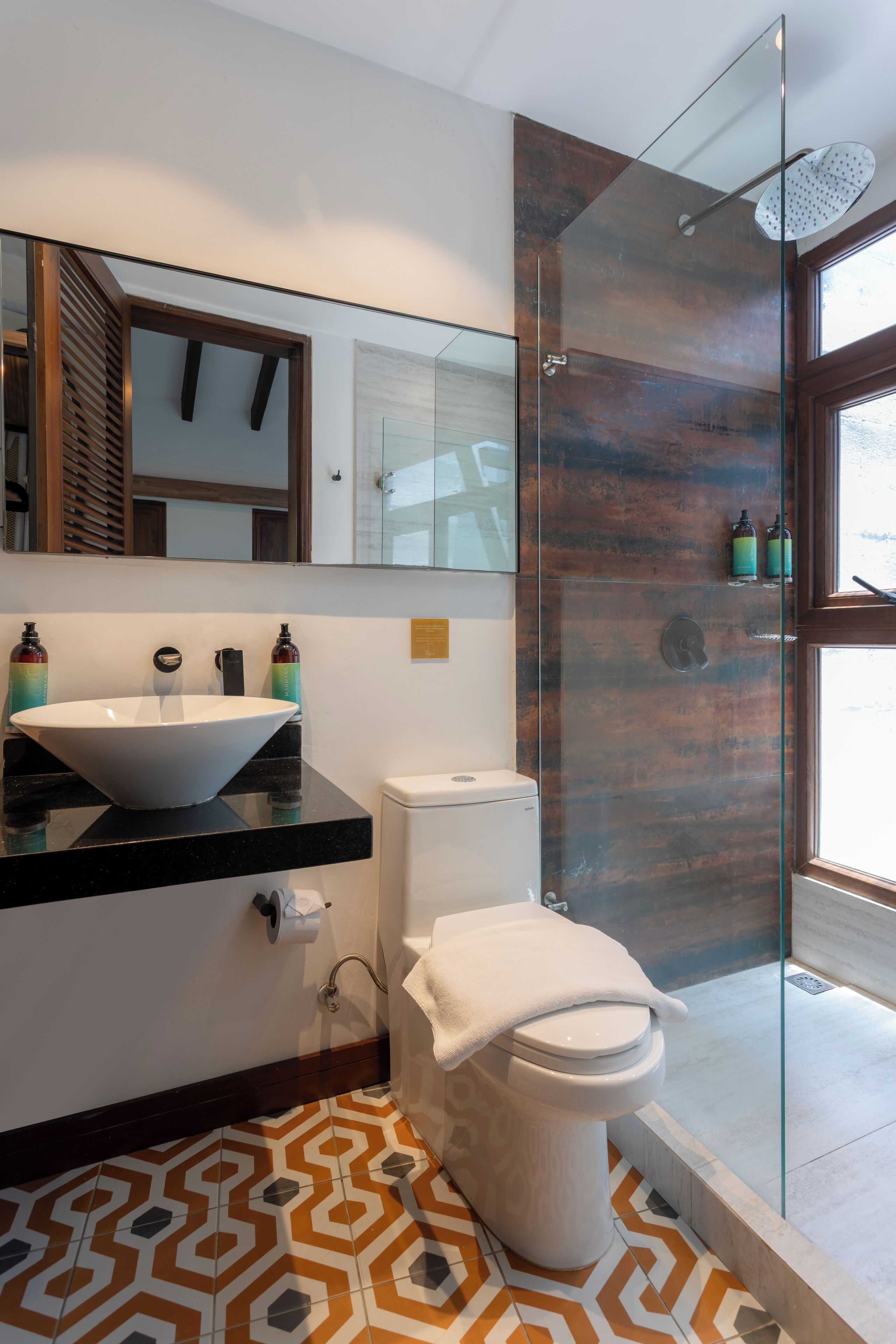 Een moderne badkamer met een grote spiegel, een witte wasbak en een douchecabine van glas.