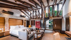 A spacious bedroom with a large bed, a sofa, and a chair. There is a staircase leading to an upper level. - Alko Hotel Casa Nispero (Cali)