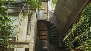 A spiral staircase in a courtyard surrounded by lush greenery and concrete structures. - Alko Hotel Casa Nispero (Cali)
