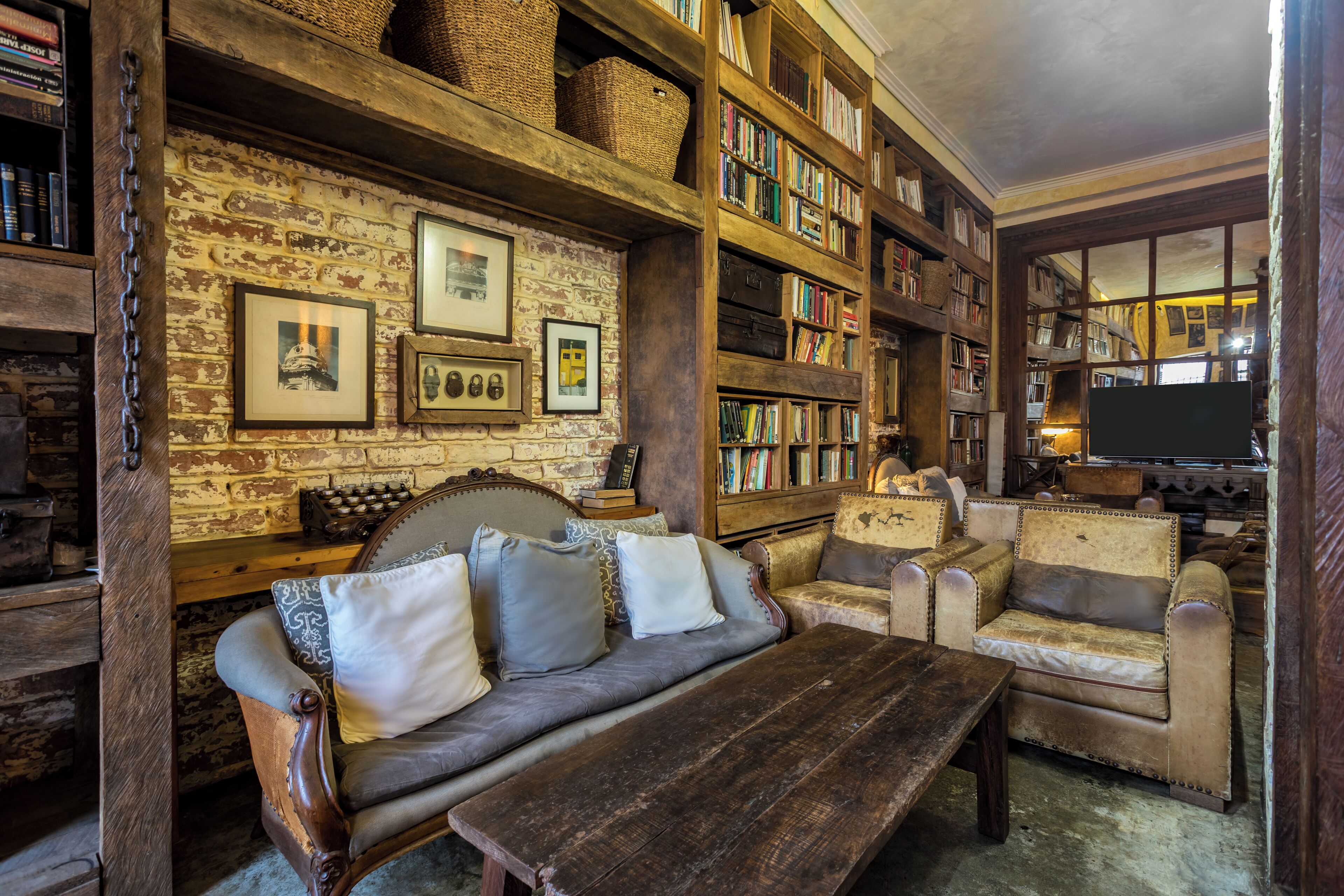 A cozy library with bookshelves, a wooden bench, and a sofa.