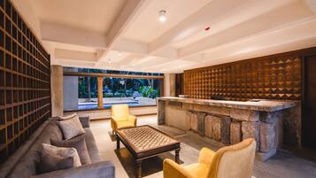 A modern lounge area with a stone bar, cushioned seating, and a large window offering a view of greenery.