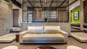 A modern living room with a beige sofa, a coffee table, and a decorative screen.