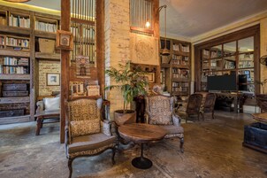 Una biblioteca con estanterías, una planta grande y muebles antiguos.