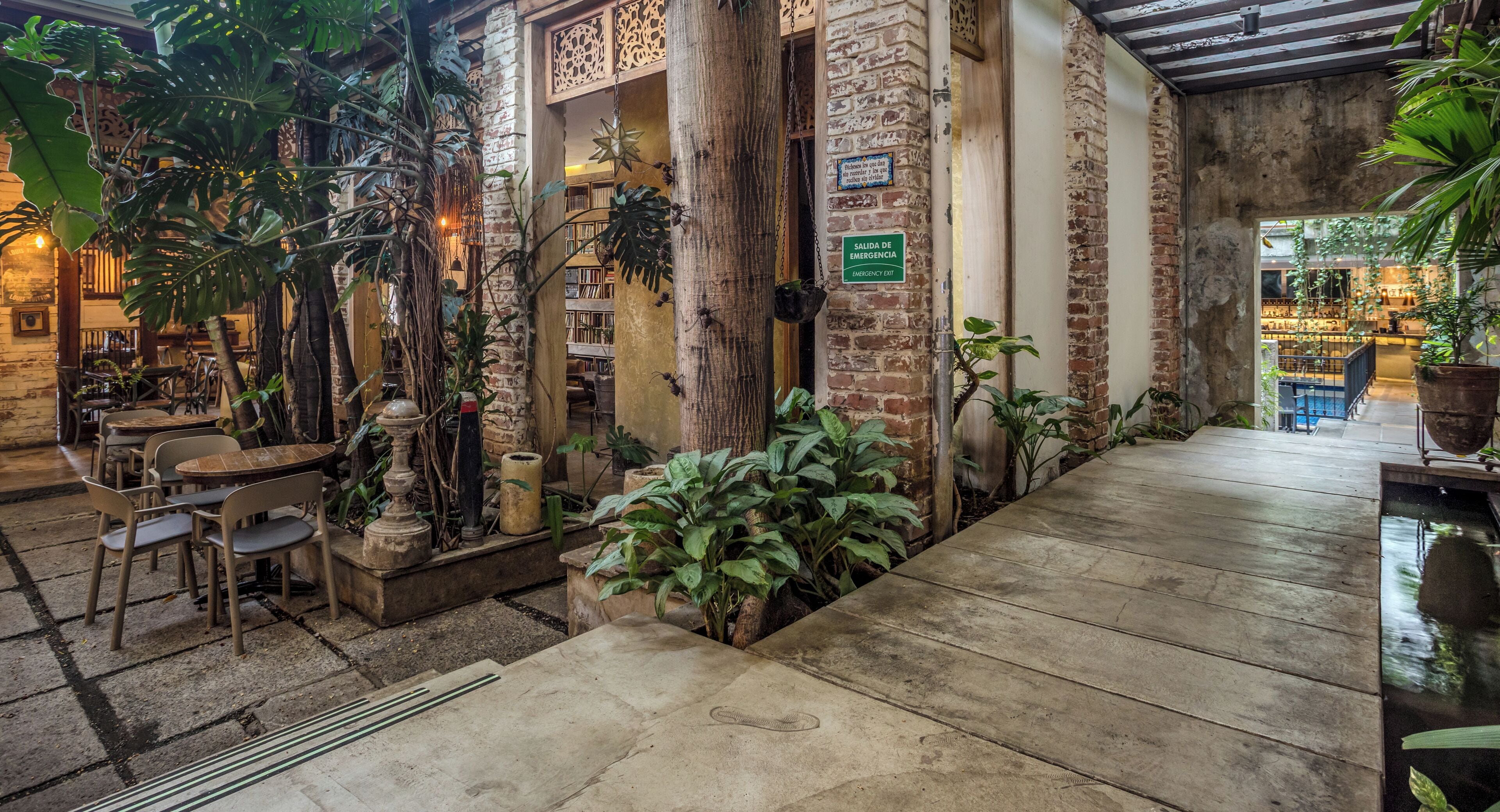 A cozy indoor area with brick walls, wooden tables, and potted plants.