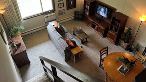 Una sala de estar con sofá, mesa de centro, televisor y estantería.