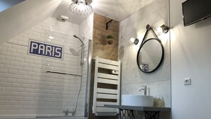Een moderne badkamer met een douchecabine van glas, een witte wastafel en een spiegel.