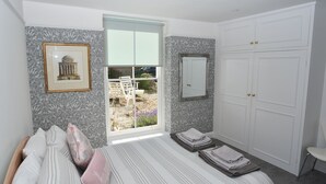 Un dormitorio con cama, ventana, armario y un cuadro en la pared.