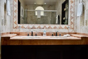 A bathroom with a large mirror, two sinks, and a shower.