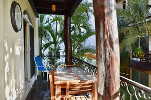 A wooden table and chairs on a balcony with a view of palm trees.