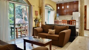 Una sala de estar con un sofá, una mesa de centro de vidrio y vistas a un balcón con mobiliario exterior.