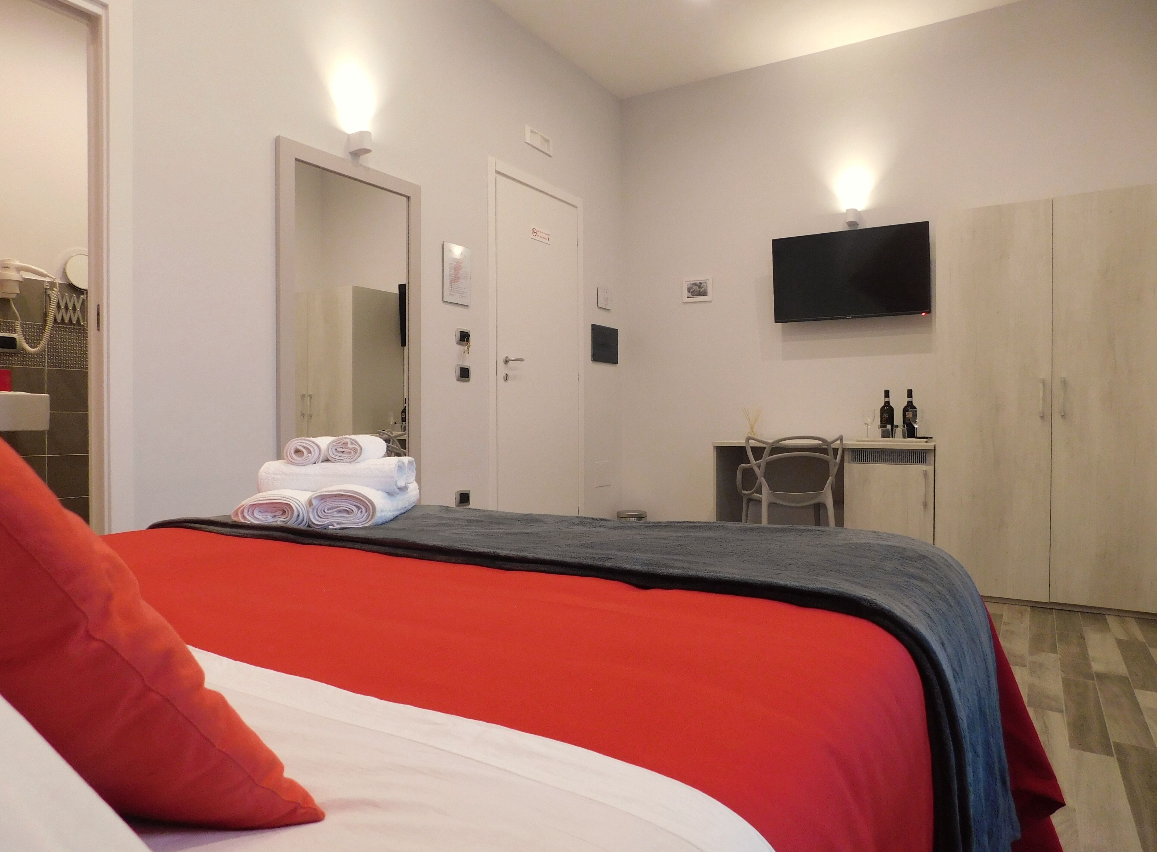Ett hotellrum med en säng, ett skrivbord, en stol, en tv och en garderob.